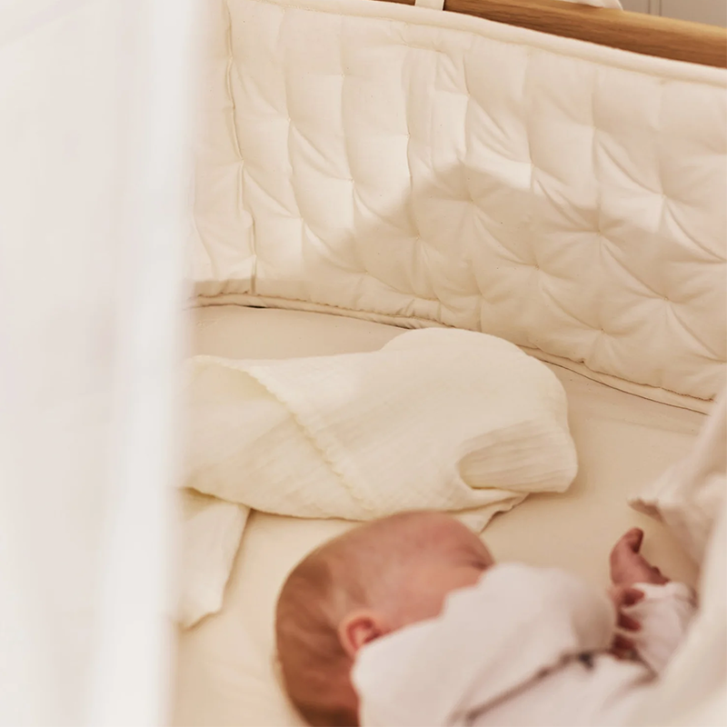 Baby schläft in einem Babybett mit dem Dear April Babynestchen in Pure Nature. 