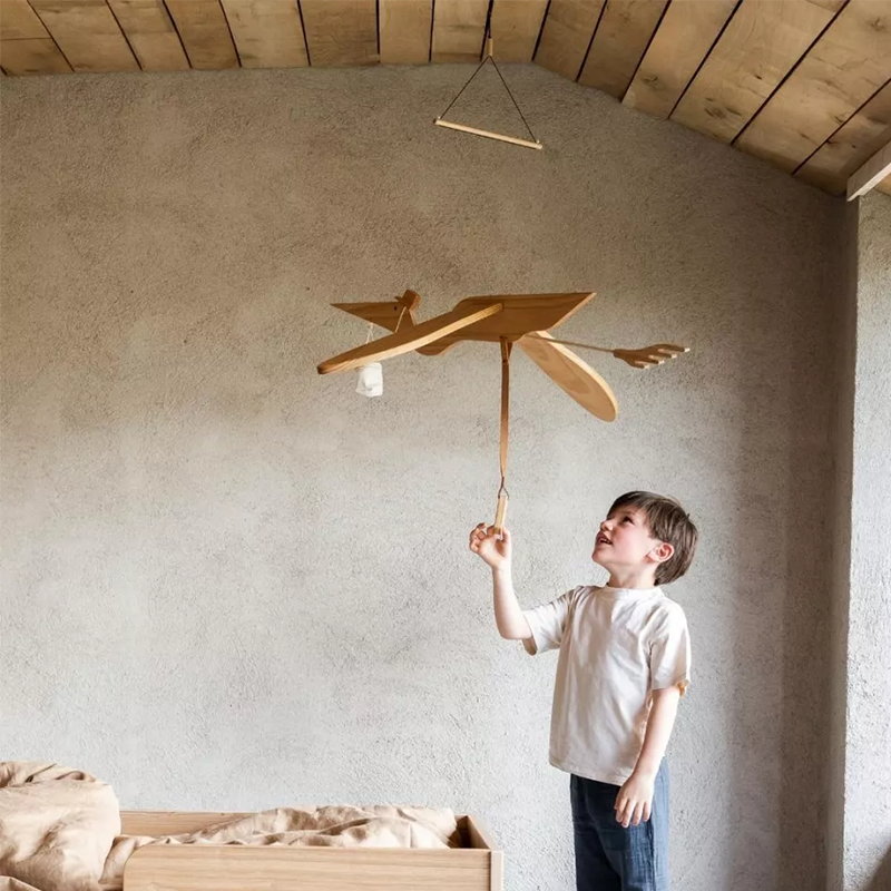 Pelikan-Mobile aus Holz fürs Kinderzimmer von Quax. Junge zieht am Lederband des Mobile.