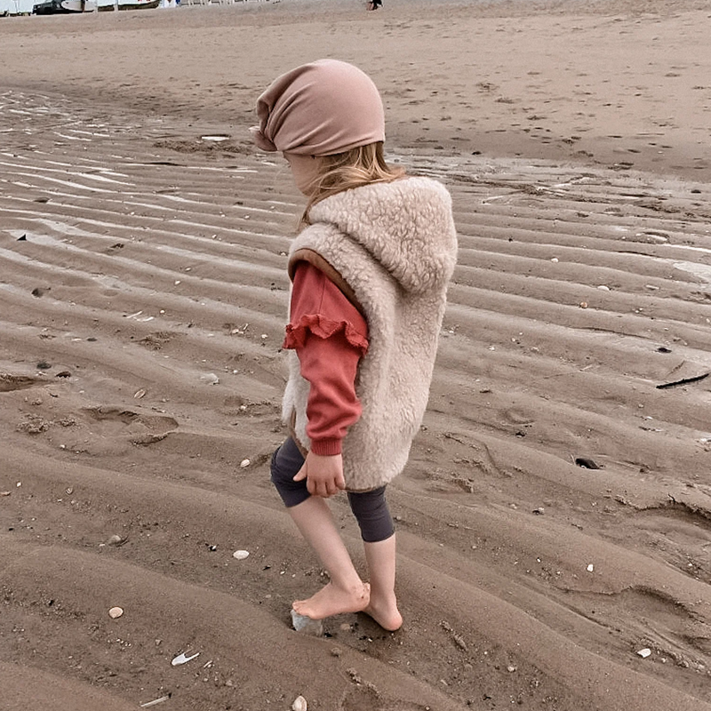 Kind am Strand mit beiger Wollweste