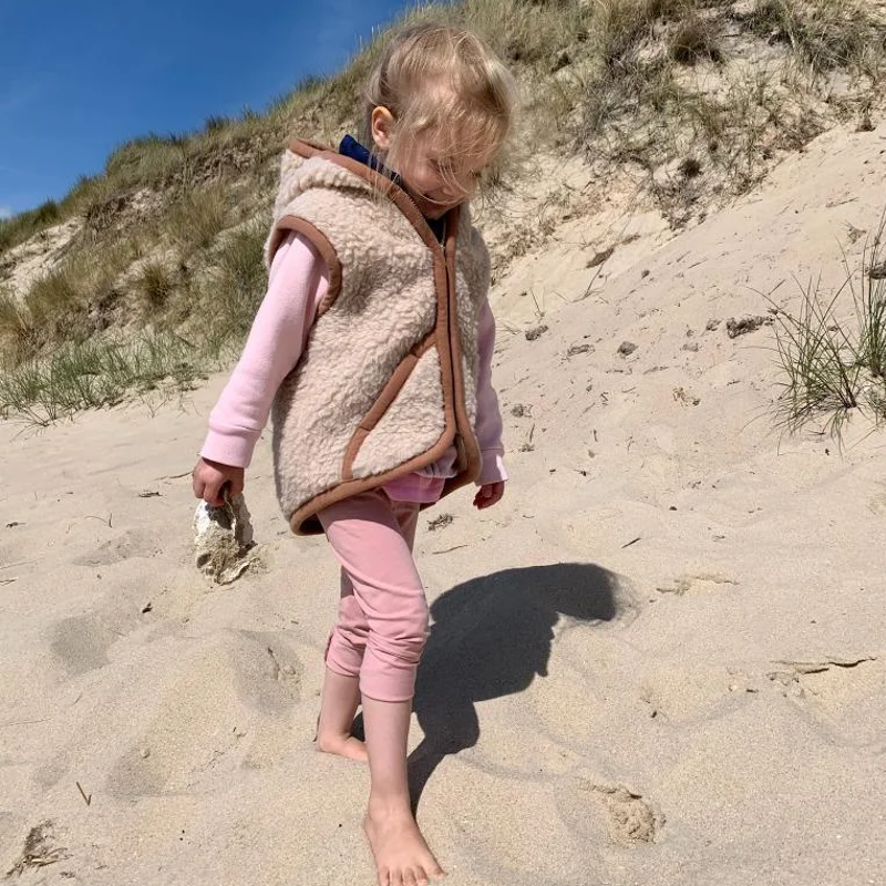 Kind am Strand mit beiger Wollweste