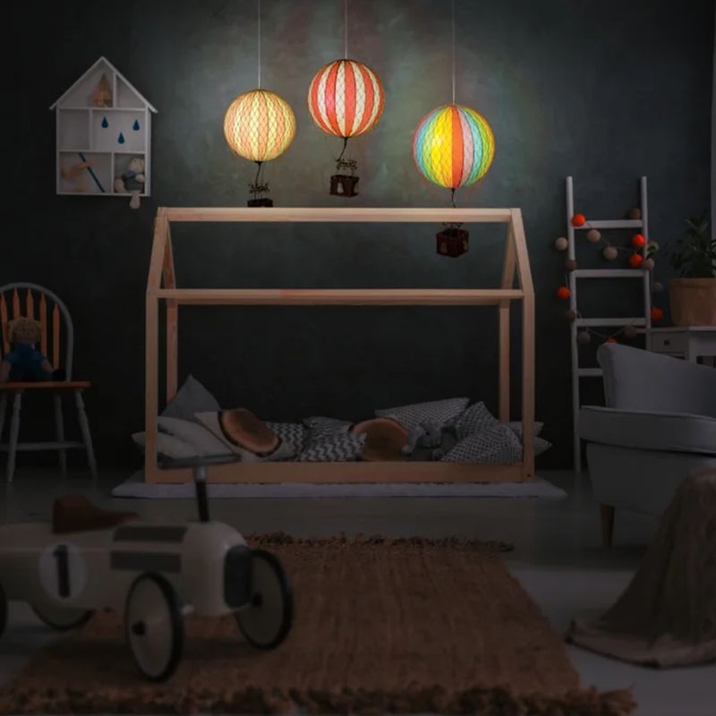 Deko LED-Heissluftballone in verschiedene Farben über Kinderbett.