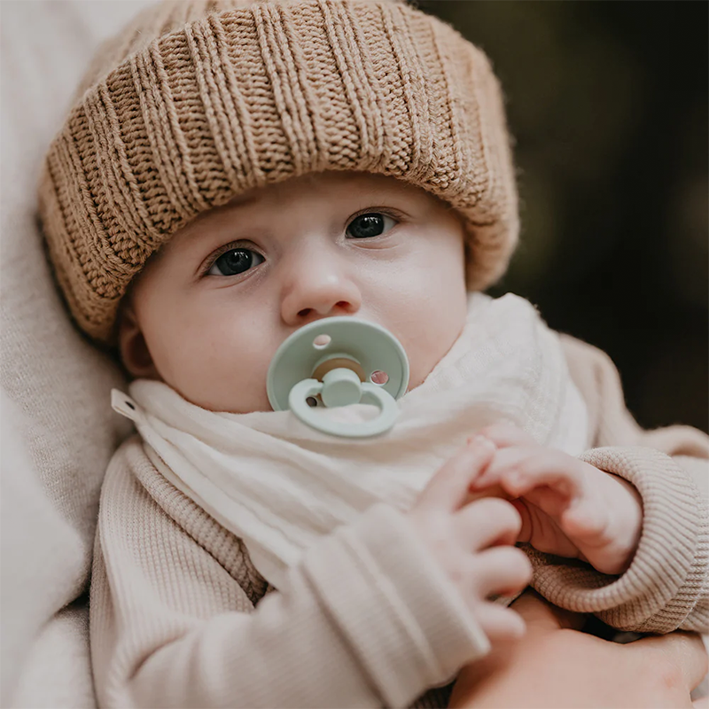 Baby trägt Strickmütze und Baby Bandana in Weiss von Bibs. 