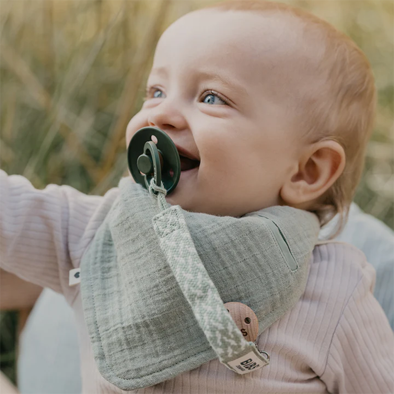 Baby trägt Baby Bandana in Grün von Bibs. 