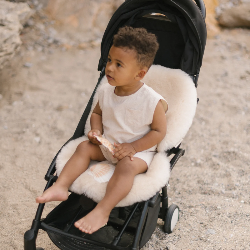 Kind in schwarzem Buggy mit beiger Schaffell-Sitzauflage
