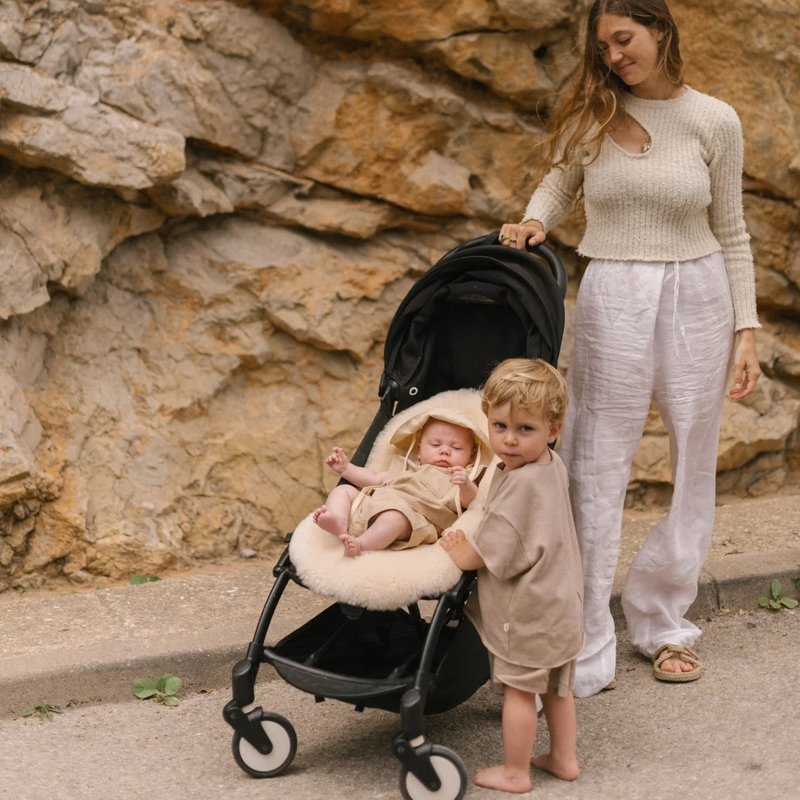 Baby in schwarzem Buggy mit beiger Schafffell-Sitzauflage