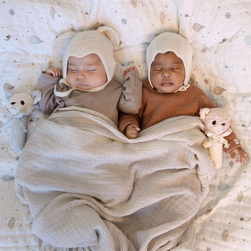 Zwei Babys schlafen schön eingekuschelt neben zwei der Bären-Rasseln aus der Serie von Cam Cam Copenhagen