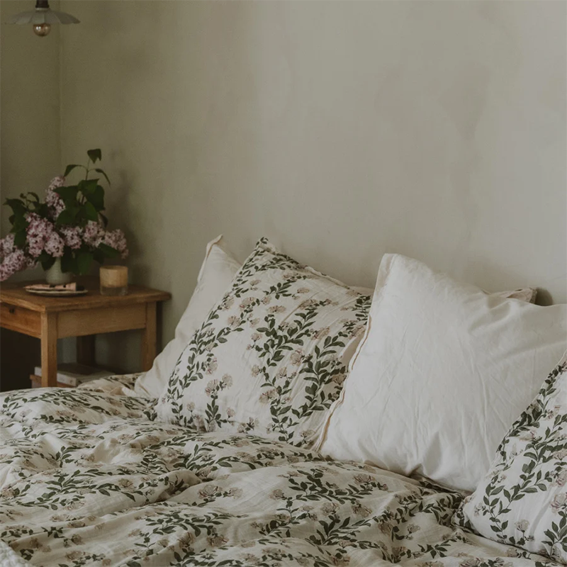 Nahaufnahme von Bett mit Nachttisch und der Bettwäsche Set aus Musselin in Beige mit leichtem Blumenmuster von Garbo&amp;Friends auf dem Bett.