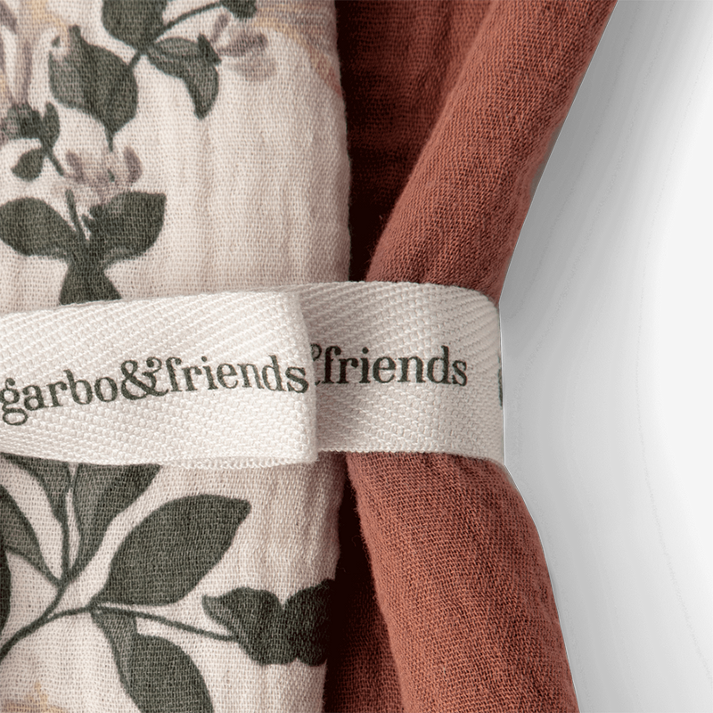 Nahaufnahme 2er Set Mulltücher zusammengefaltet eines in Beige mit Blumen- und Blättermuster und eines in Rot von Garbo and Friends.