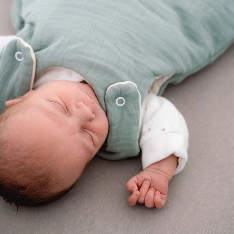 Baby schläft und trägt den Julius Zöllner Babyschlafsack in Grün. 