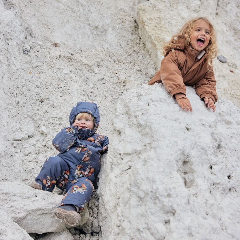 Kinder spielen, angezogen mit Nohr Schneeanzügen in den Steinen am Meer
