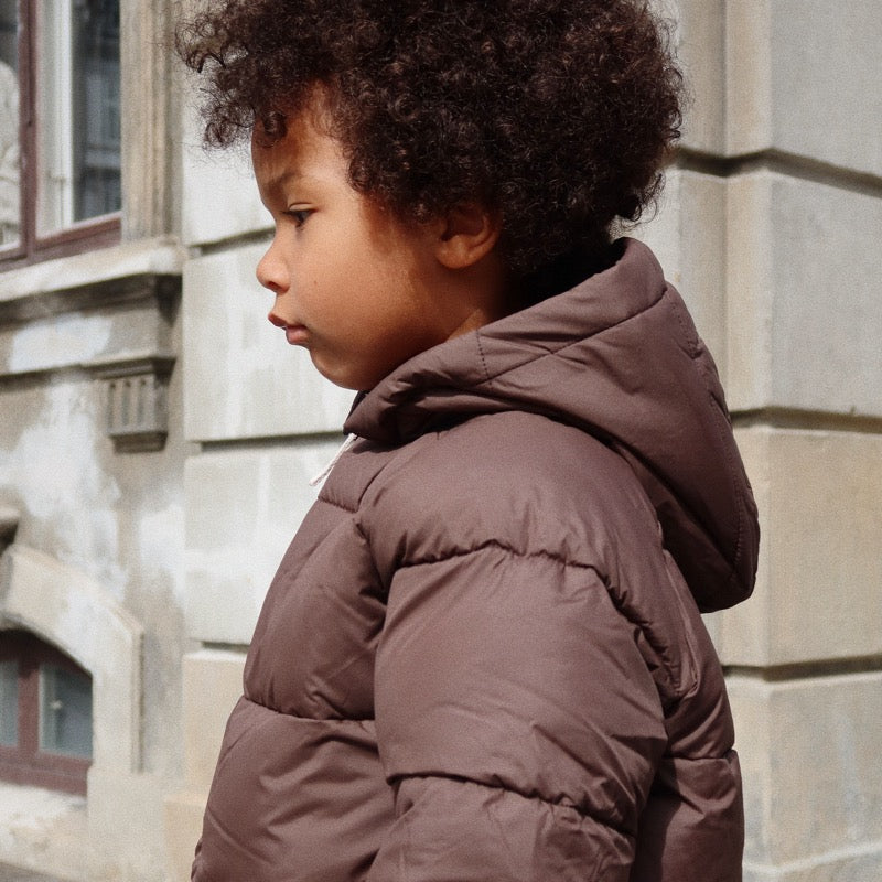 Kind trägt die warme Puffer-Jacke / Daunen-Jacke von Konges Sløjd in Chocolate Brown