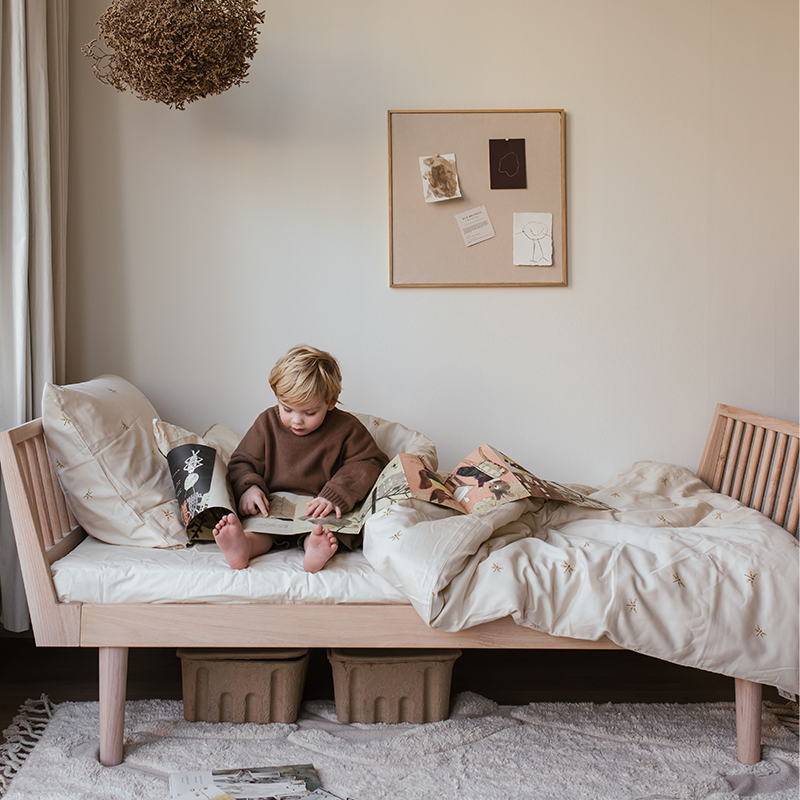 Junge liest ein Buch auf dem Kas Kopenhagen Junior Bett in der Farbe Light Oil Oak