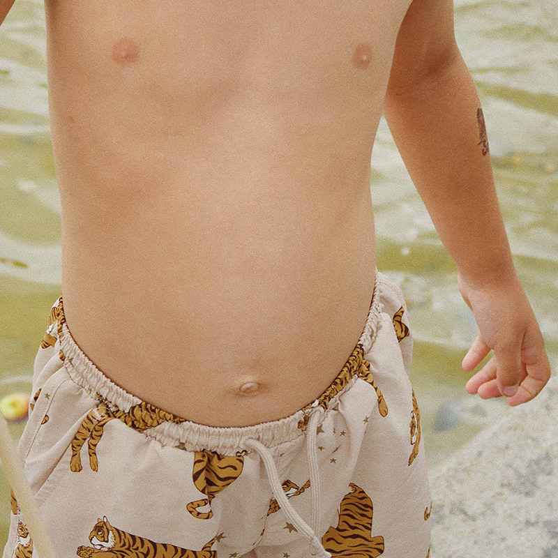 Junge trägt Badehose für Kinder in Beige mit Tigerprint von Konges Slojd.