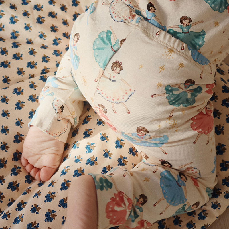 Baby kriecht auf Krabbeldecke und trägt Konges Slojd Baby Bekleidungsset bestehend aus Langarmbody und Leggings in Beige mit Ballerinamuster. 