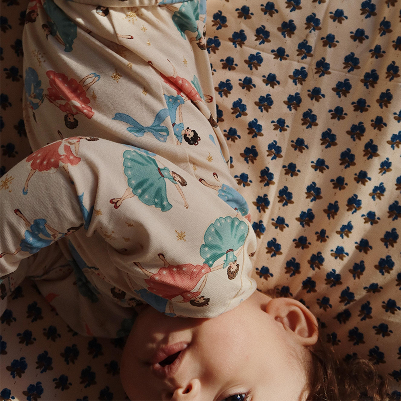 Baby liegt auf Krabbeldecke und trägt einen Body von mit Ballerinamuster von Konges Slojd.