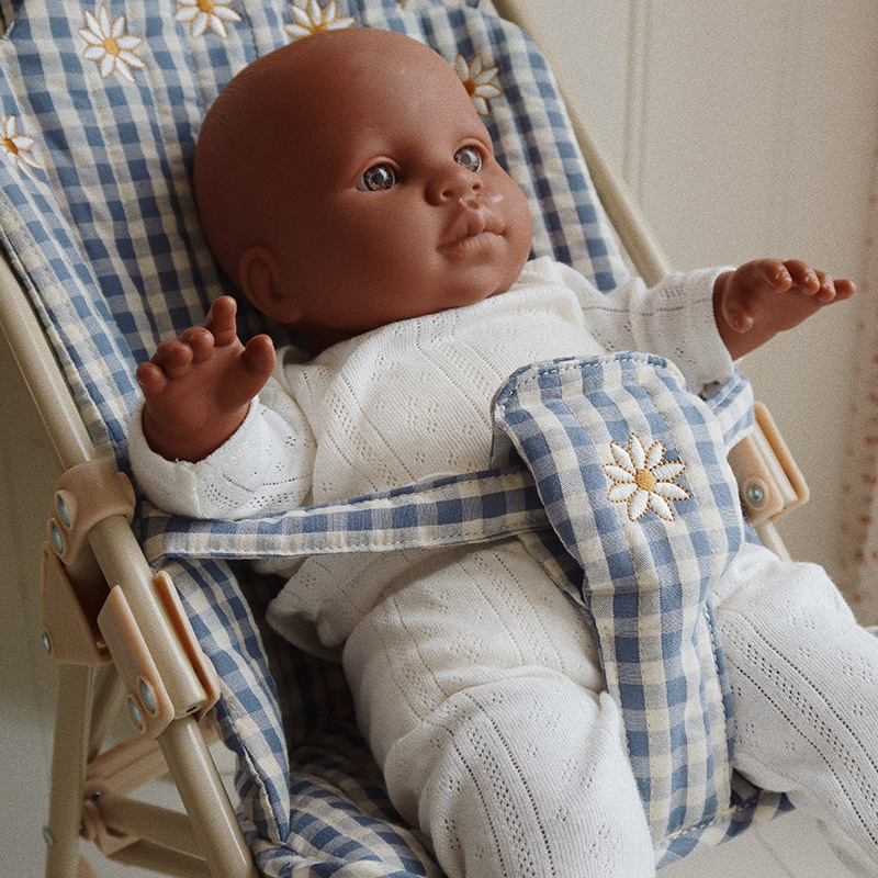 Puppe sitzt im Blau-weiss karierter Buggy für Puppen von Konges Slojd.