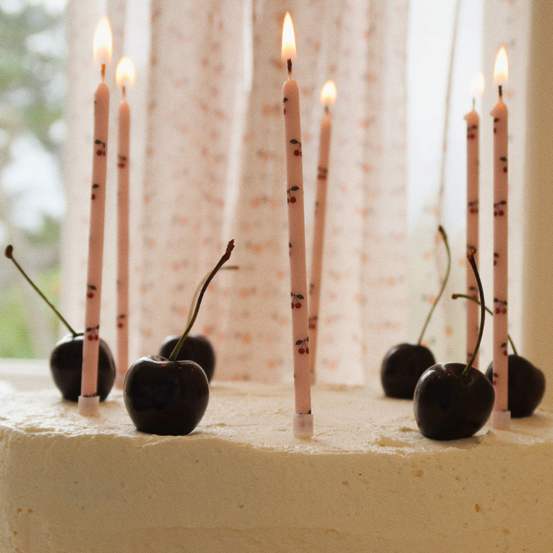 Geburtstagskerzen in rosa mit Kirschmuster von Konges Slojd brennen auf einer Kirschtorte.