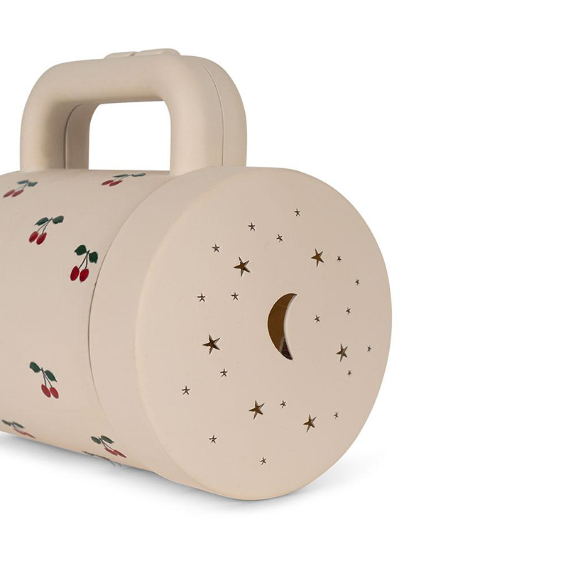 Projektortaschenlampe in Beige mit Aufsatz, um Sternen- und Mondmotive an die Wand zu projizieren von Konges Slojd von vorne.