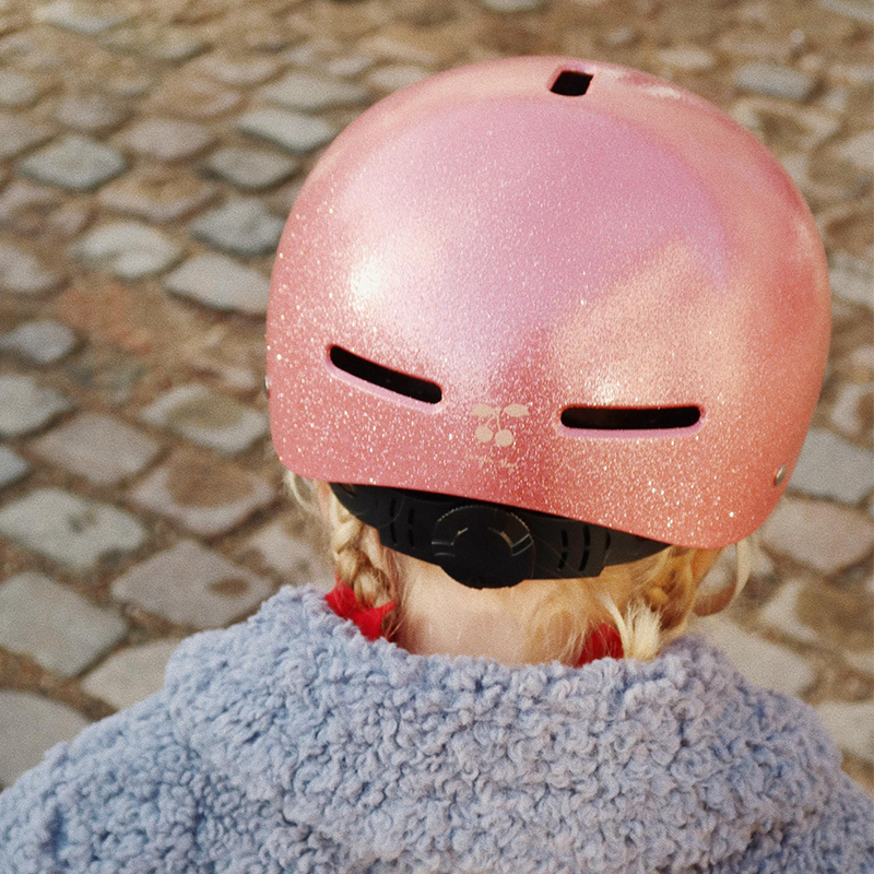 Mädchen von hinten, sie trägt einen pinken, glitzernden Fahrradhelm für Kinder von Konges Slojd. 