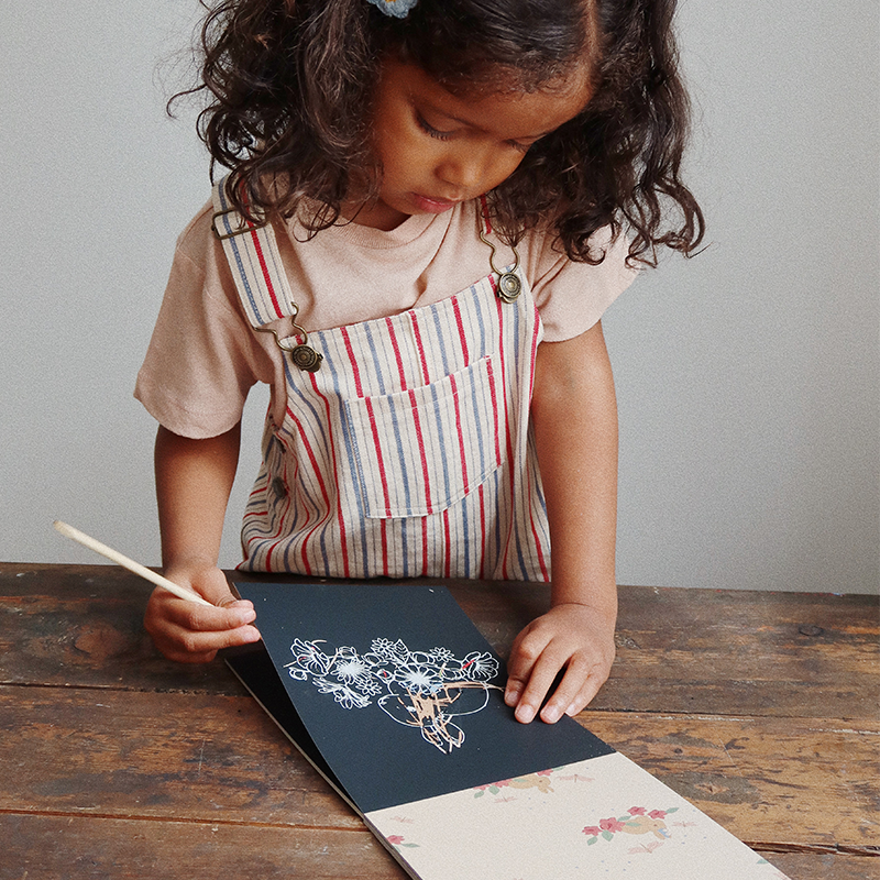 Mädchen kratzt in Kratzbuch von Konges Slojd.