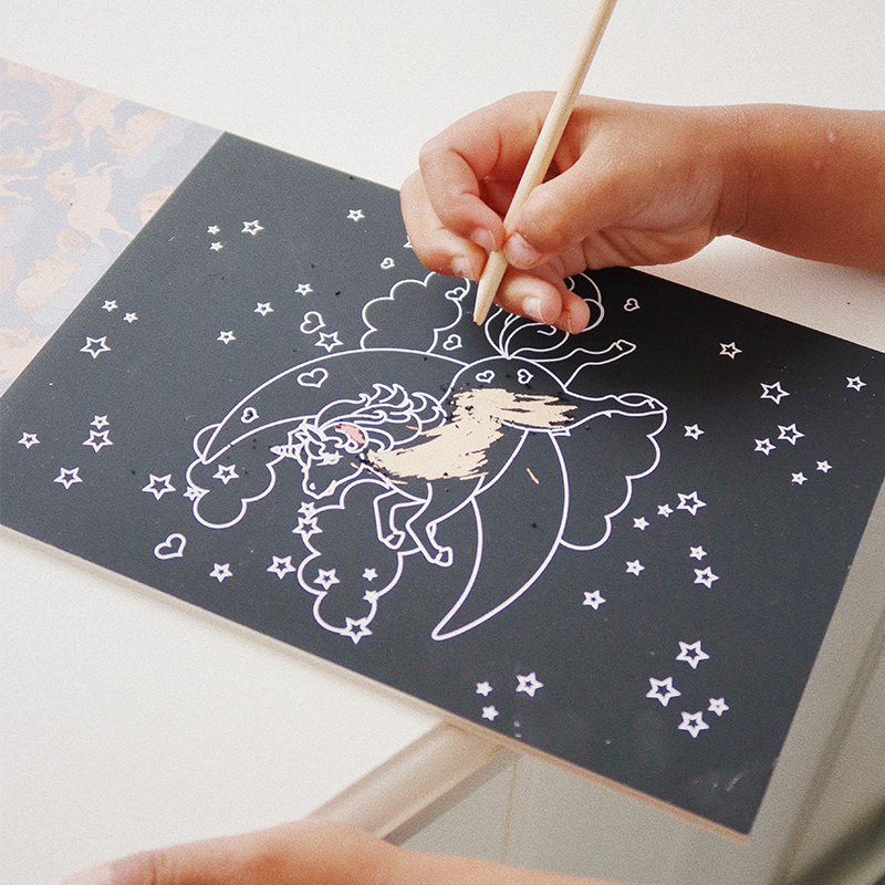 Hand kratzt in Kratzbuch Einhorn.