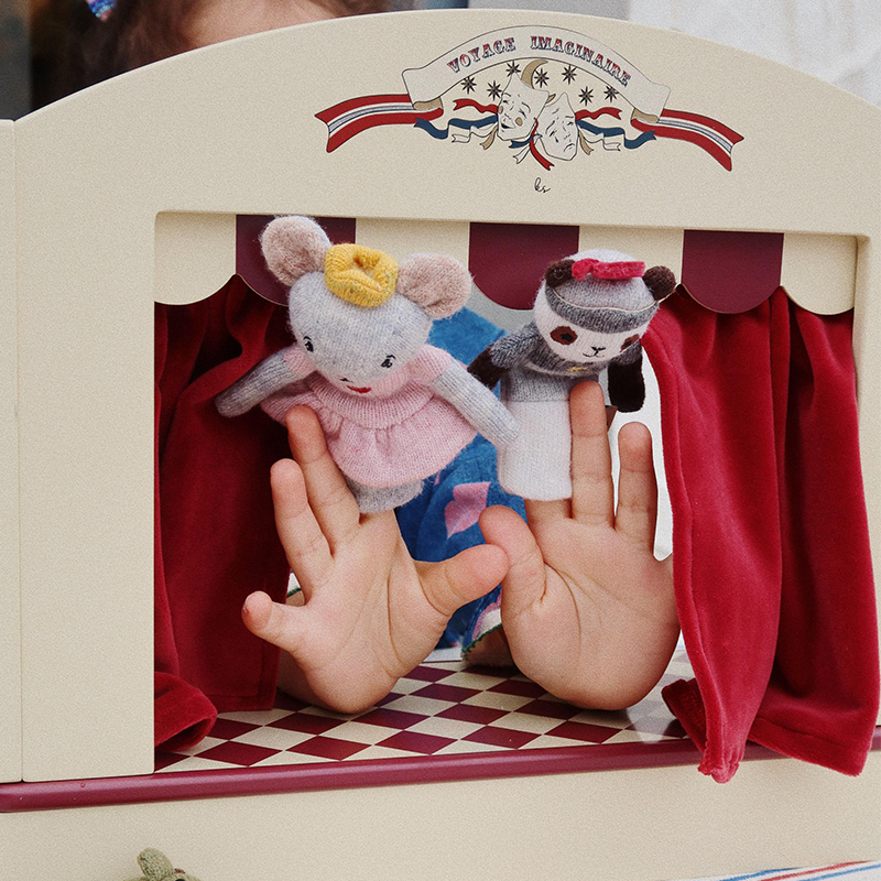 Kinderhände sind im Puppentheater aus Holz mit rotem Samtvorhang von Konges Slojd zu sehen.
