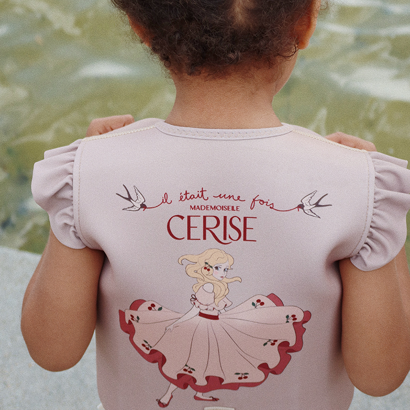 Mädchen trägt Schwimmweste für Kinder in lila mit Rüschen an den Schultern und Prinzessinnenprint auf dem rücken von Konges Slojd.