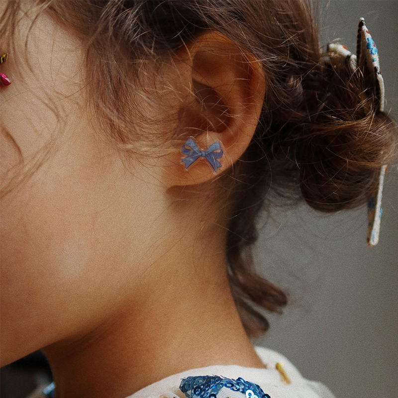 Nahaufnahme von Kinderohr mit blauem Ohrringaufkleber von Konges Slojd. 