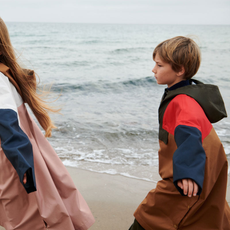 Junge am Meer trägt einen Regenmantel / Poncho &quot;Marcel&quot; in toller Farbkombination von Liewood