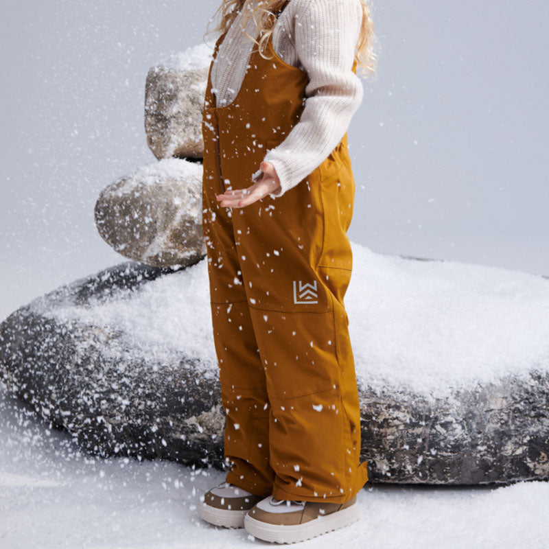 Kind im Schnee mit Schneehose in Golden Caramel von Liewood