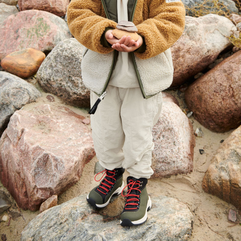 Kind mit den Wanderschuhen &quot;Ava&quot; von Liewood in Khaki-Grün und Schwarz mit roten Schuhbändeln