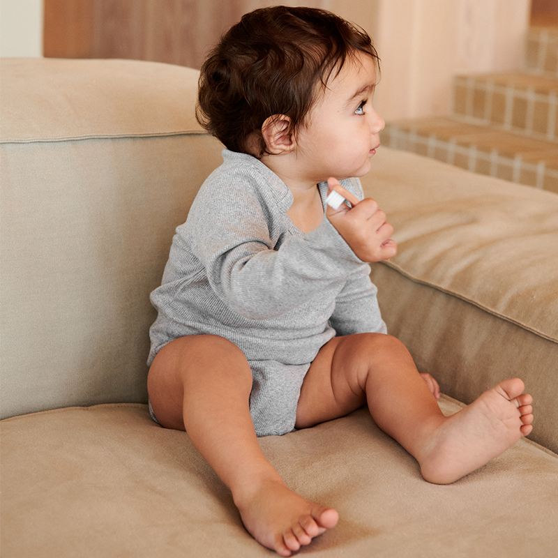 Kleinkind sitzt auf Sofa und hat die Zahnbürste von Liewood in der Hand.