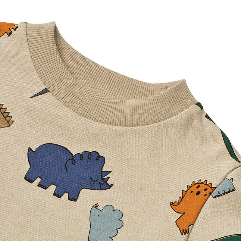 Nahaufnahem vom Kragen vom Pullover in Beige für Kinder mit buntem Dinosauriermuster von Liewood.