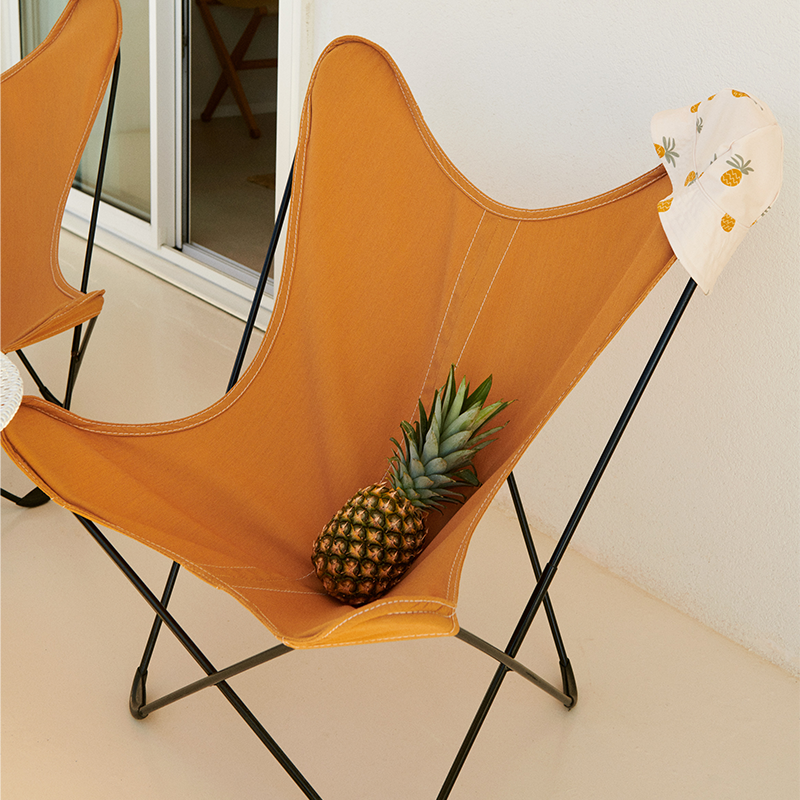 Liewood Sonnenhut Josefine mit Ananasmuster auf einem Stuhl.
