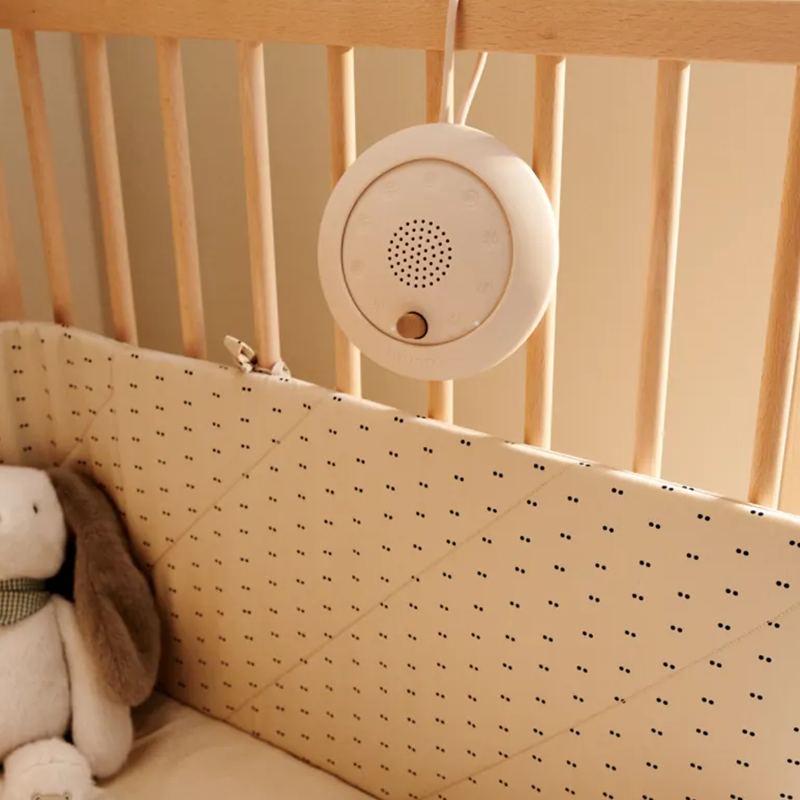Einschlafhilfe Lautsprecher für Babys in Beige von Liewood hängt an Babybett.