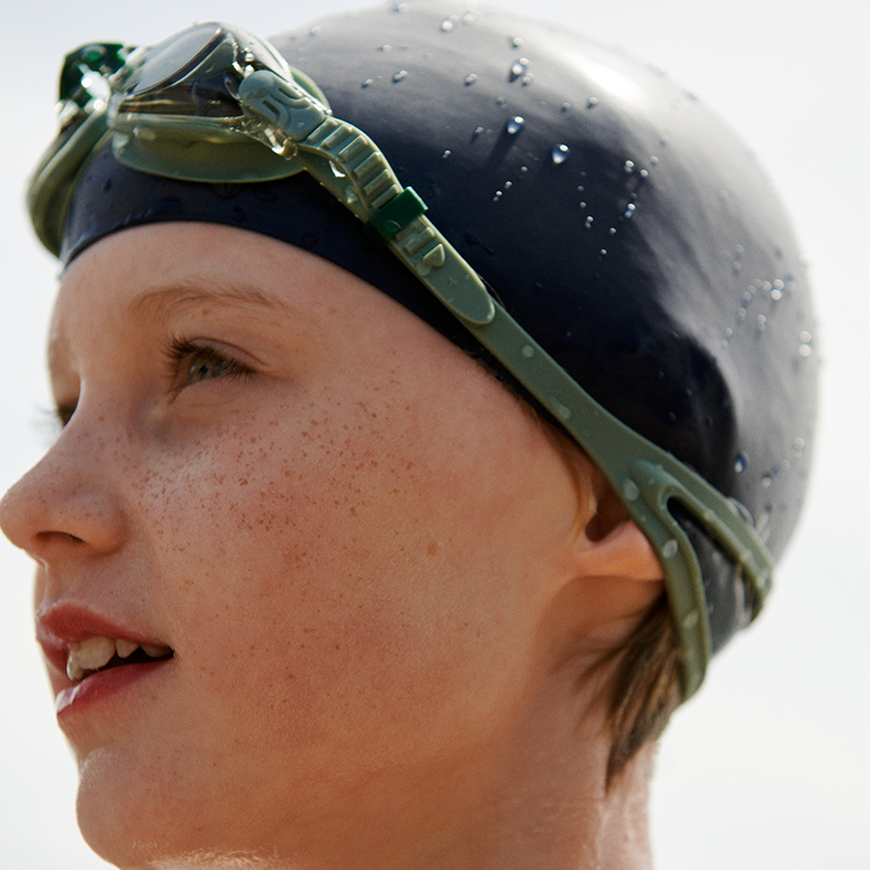 Kind trägt die Liewood Titas Schwimmbrille in Grün. 