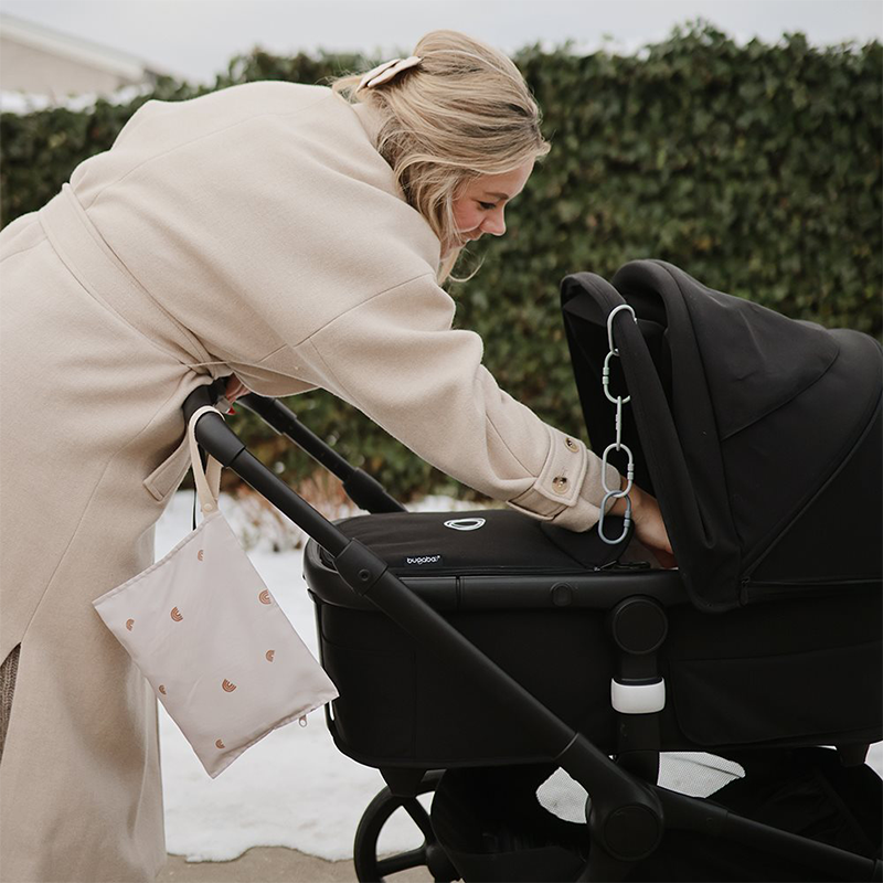 Wet Bag an Kinderwagen befestigt. Mama schiebt den Wagen.