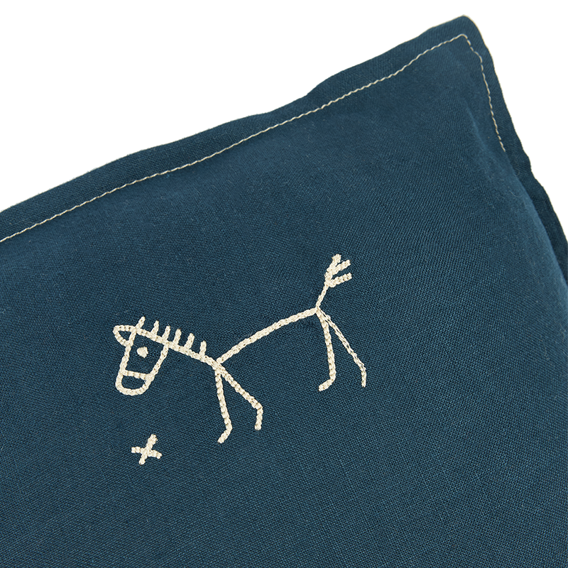 Nobodinoz Kissen in Dunkelblau mit beiger Pferdestickerei in der oberen Ecke und mit abgestepptem beigen Rand. 