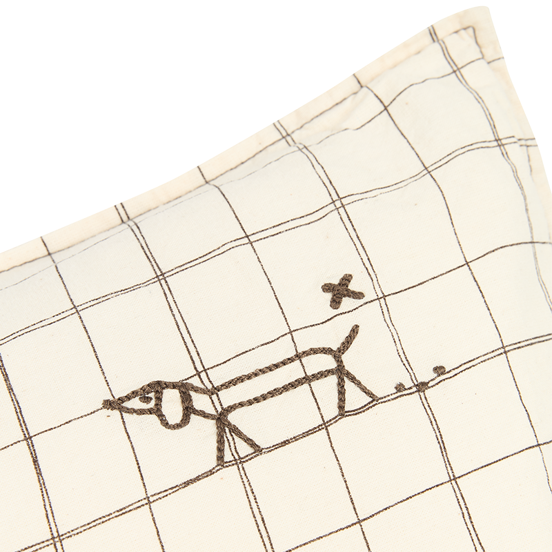 Nahaufnahme von der Stickerei vom Kissen in Beige mit Karomuster und Hundestickerei in der oberen Ecke von Nobodinoz.