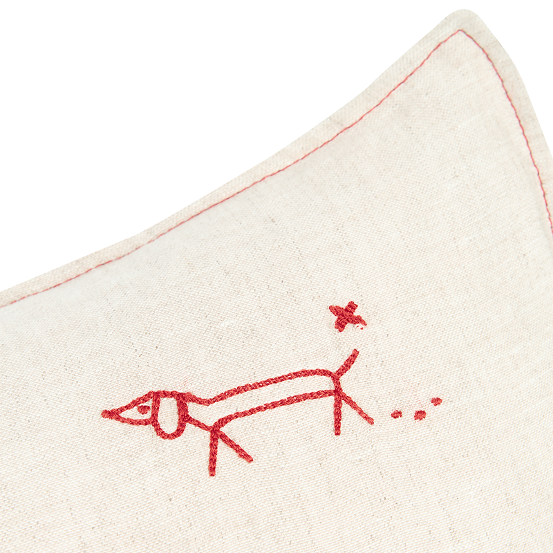 Nahaufnahme von der Stickerei vom Leinenkissen in Beige mit roter Hundestrickerei und rotem abgestepptem Rand von Nobodinoz.