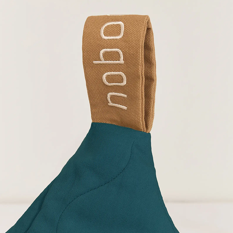 Nahaufnahme von der Trageschlaufe vom gesteppten Sitzsack in Dunkelblau mit Trageschlaufe in Braun von Nobodinoz.Gesteppter Sitzsack in Dunkelblau mit Trageschlaufe in Braun von Nobodinoz.