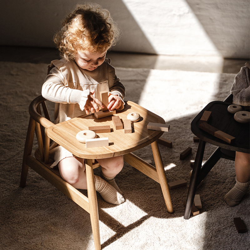 Kind spielt im Oaklings Kinderstuhl Smilla mit Tisch. 