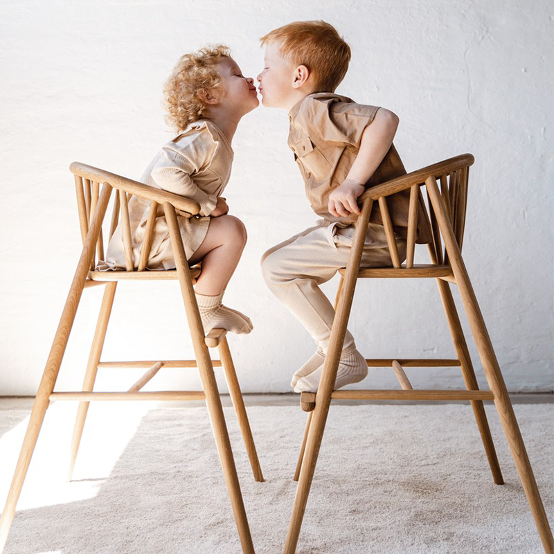 2 Kinder sitzen auf dem Oaklings &#39;SAGA&#39; Hochstuhl in Oak. 