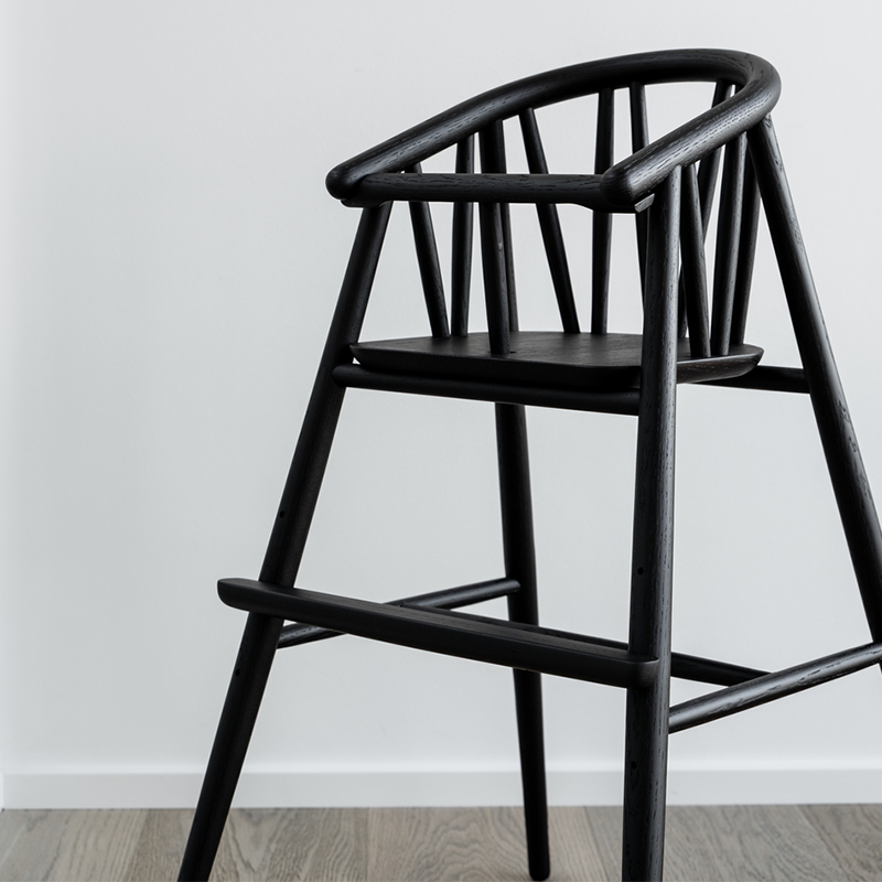 Hochstuhl für Kinder aus gebeizter schwarzer Eiche von Oaklings steht an Tisch in Wohnzimmer.