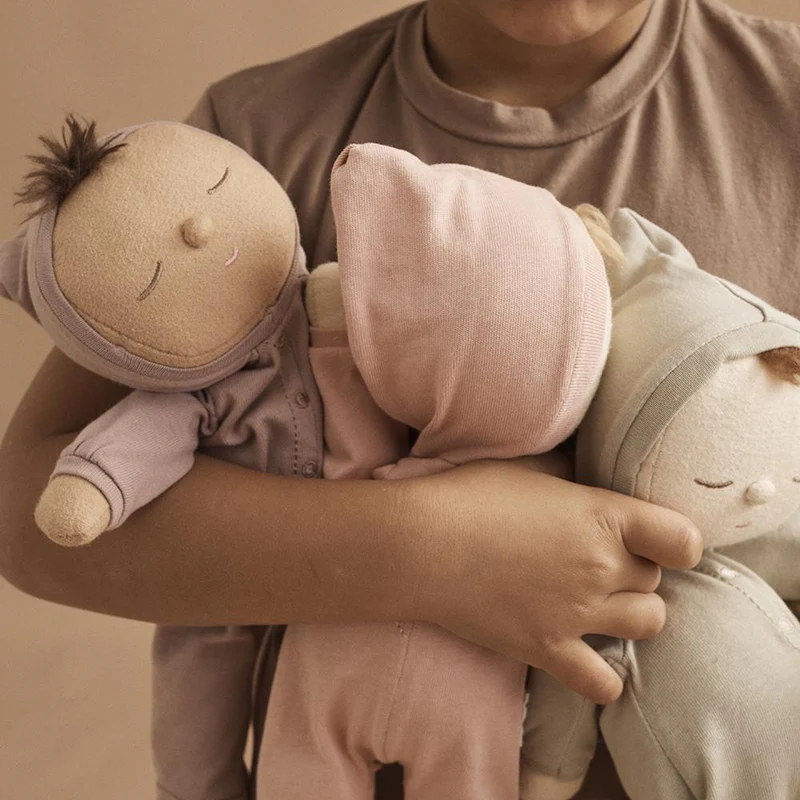 Kind hält 3 Dinkum Puppen von Oli Ella auf dem Arm.