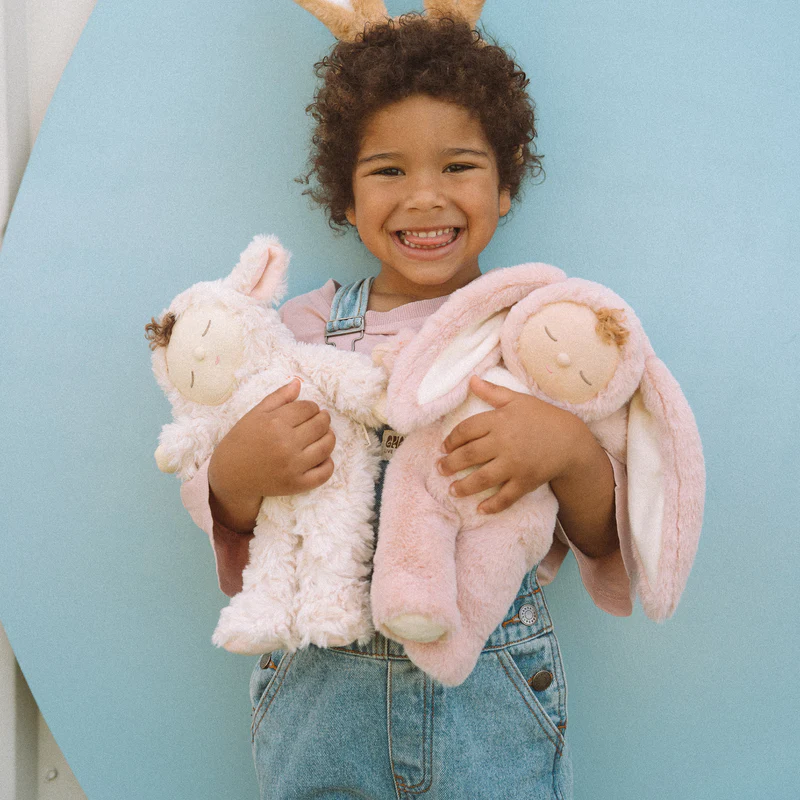 Kind trägt zwei Dinkum Puppen im Hasenkostüm von Olli Ella auf dem Arm.