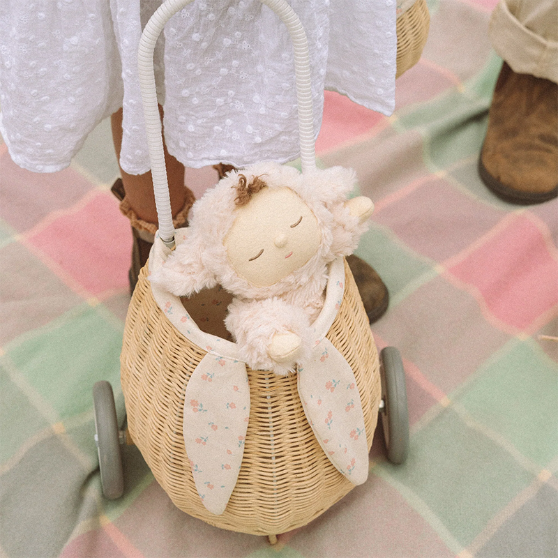 Weiche Dinkum Puppe im Lammkostüm von Olli Ella in kleinem Rattankorb mit Rädern.