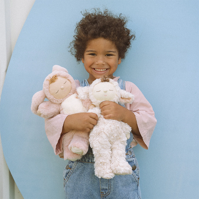 Kind hält zwei kuschelige Puppen im Hasen- und im Lammkostüm auf dem Arm.
