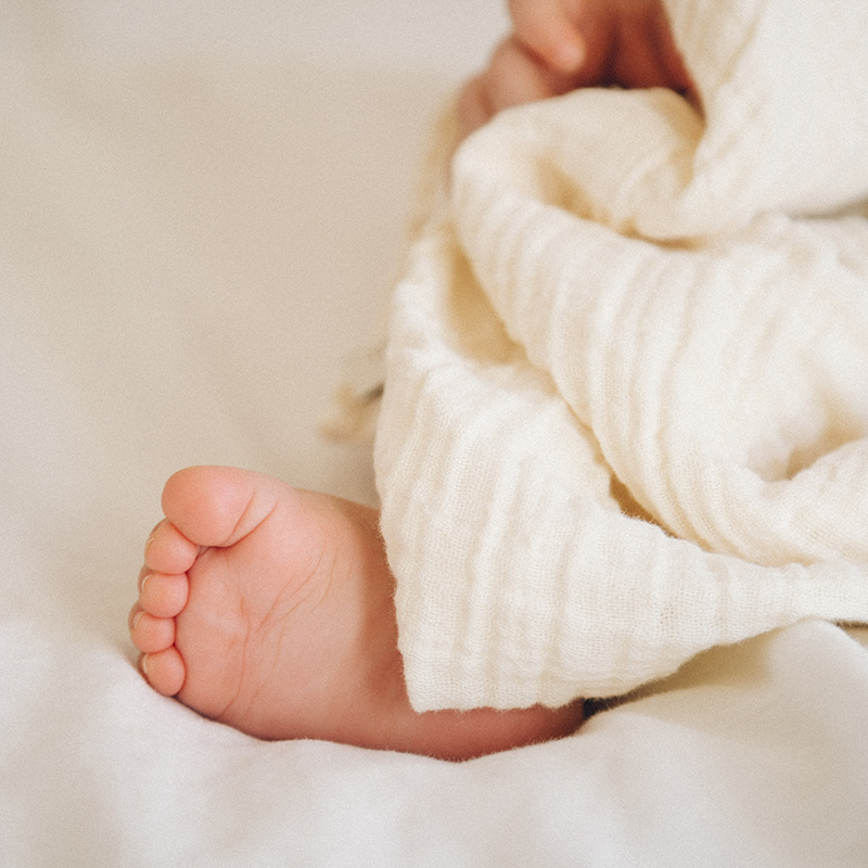 Nuschi aus Musselin in Beige von Petit Stellou auf Babyfüssen.