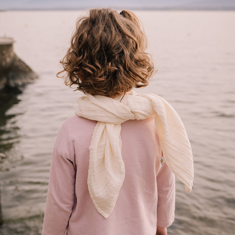 Mädchen von hinten mit Nuschi aus Musselin in Beige von Petit Stellou um den Hals.